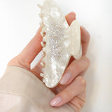 Hand holding a VESITIA bride claw clip on a white background