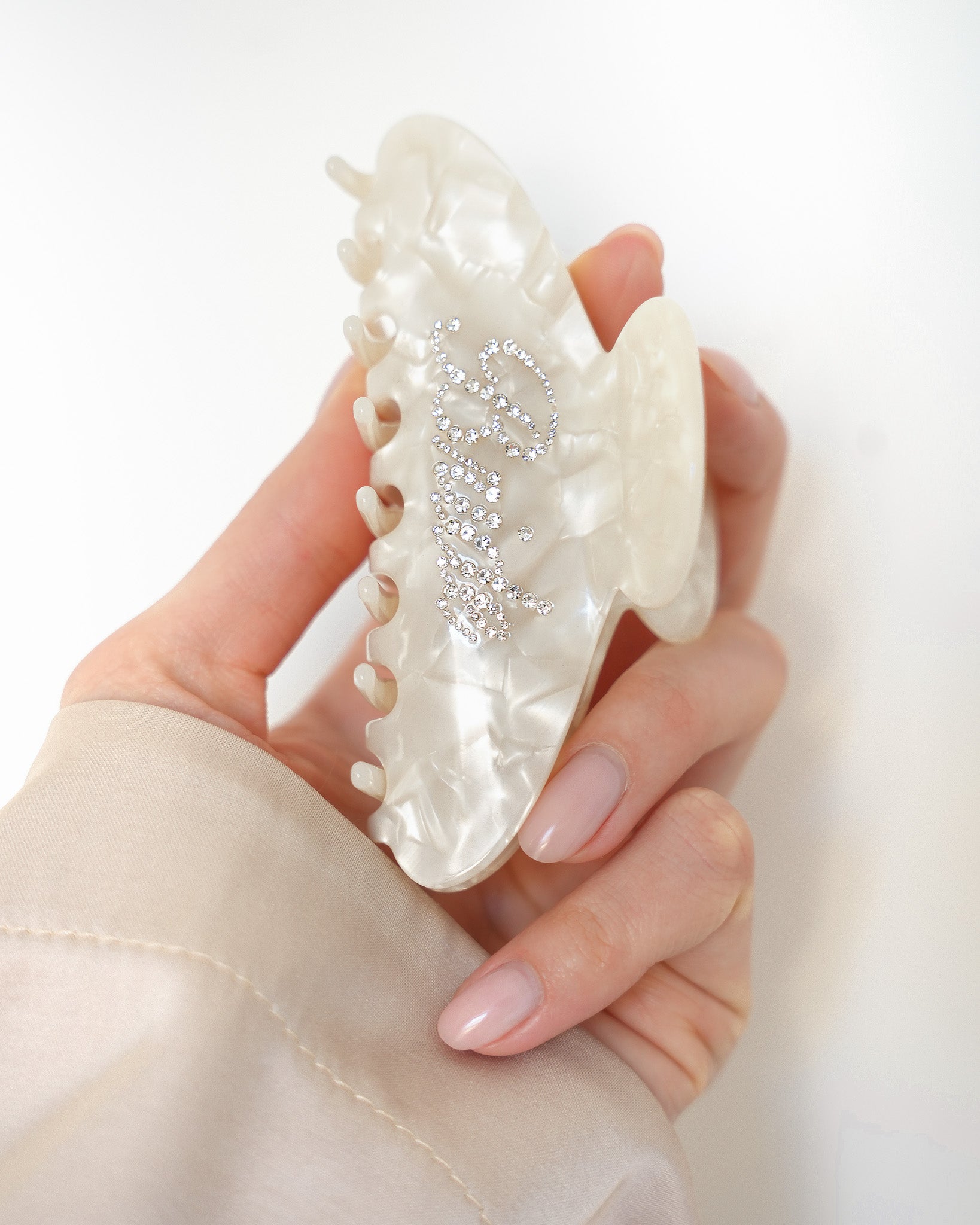 Hand holding a VESITIA bride claw clip on a white background