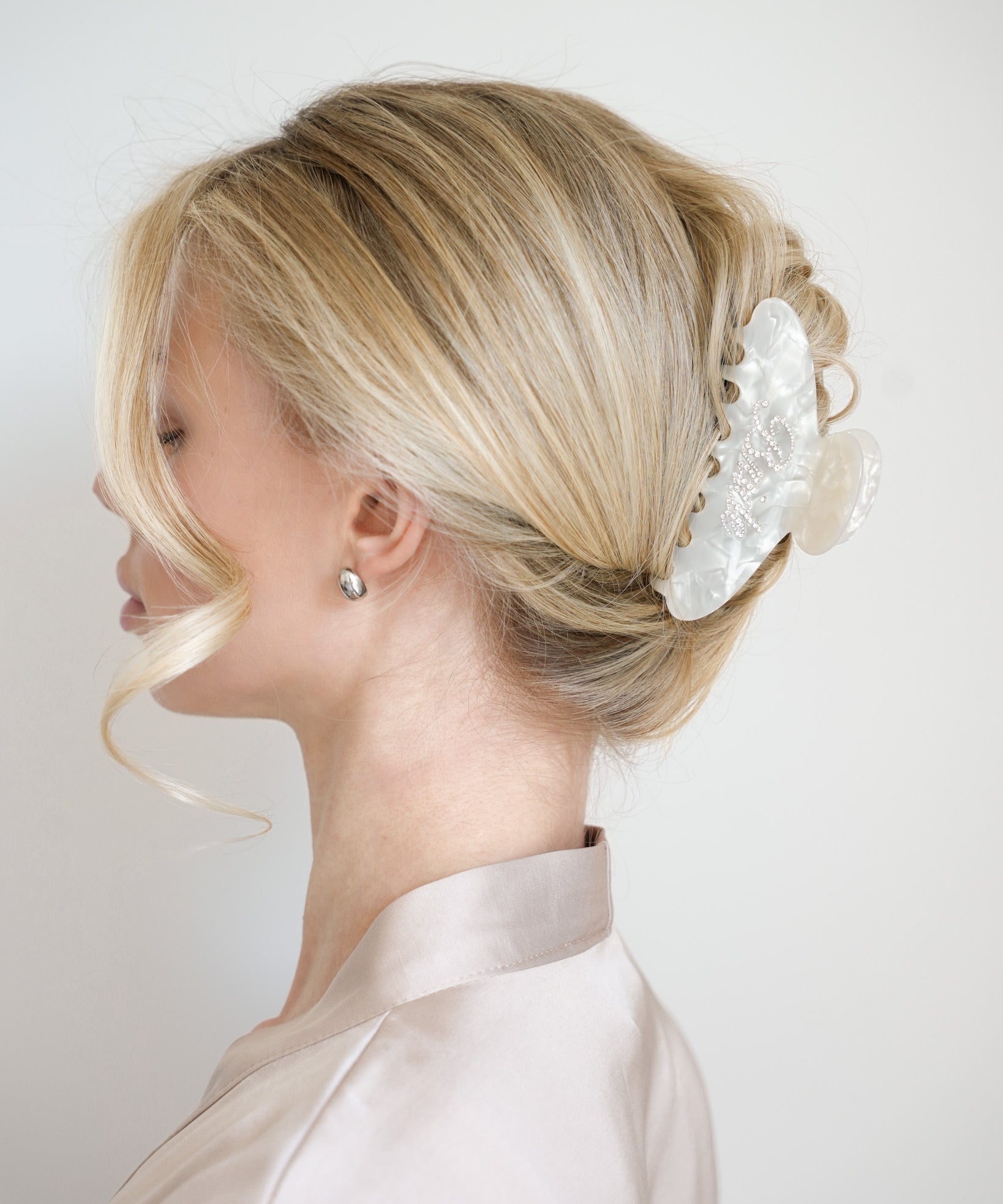Woman with styled blonde hair featuring a VESITIA bride claw clip against a plain background