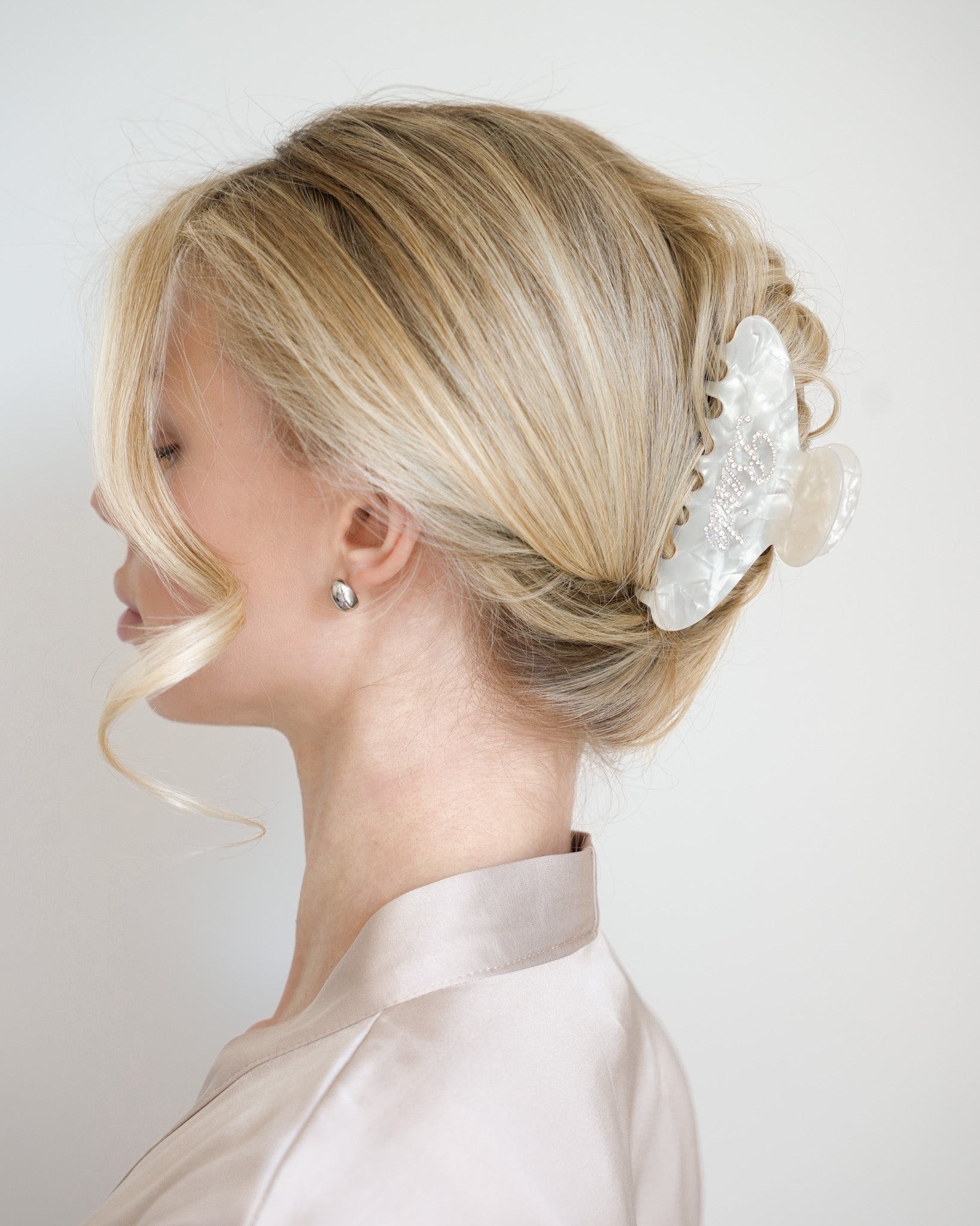 Woman with styled blonde hair featuring a VESITIA bride claw clip against a plain background