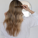 Person combing long, wavy hair with a VESITIA comb in a bathroom setting