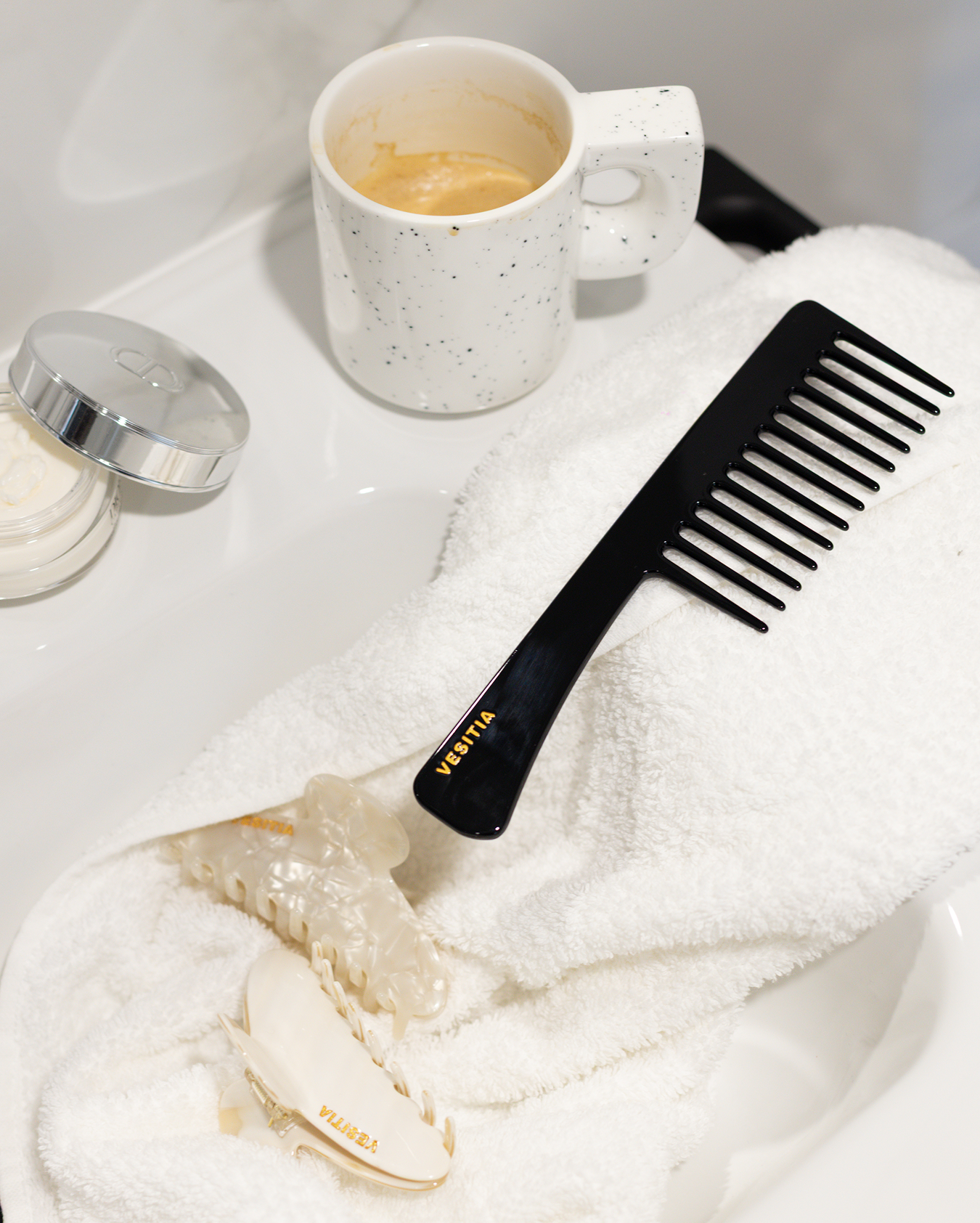 Black VESITIA com on a white towel next to a mug and jar.