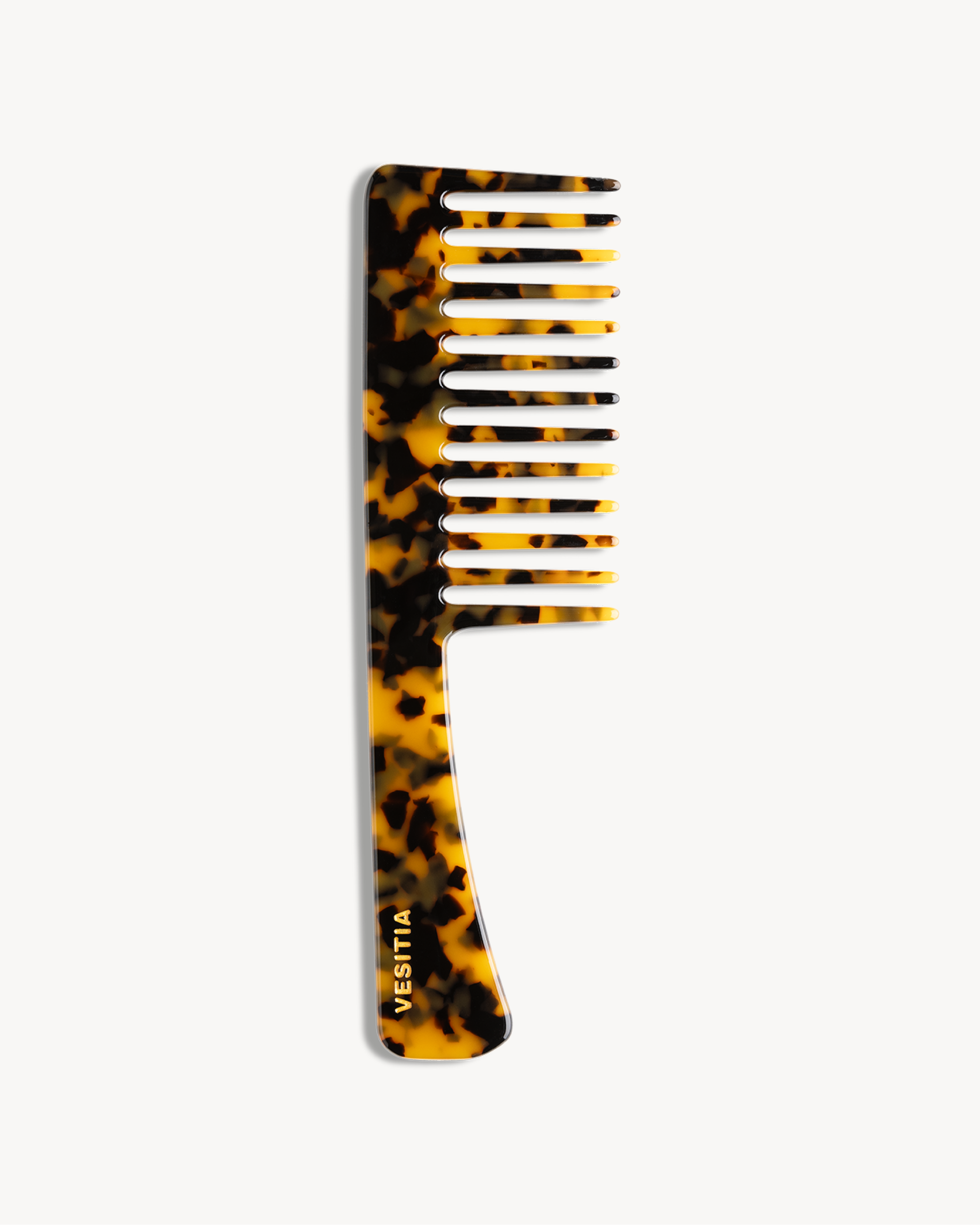 Tortoiseshell-patterned comb with 'VESITIA' branding on a white background