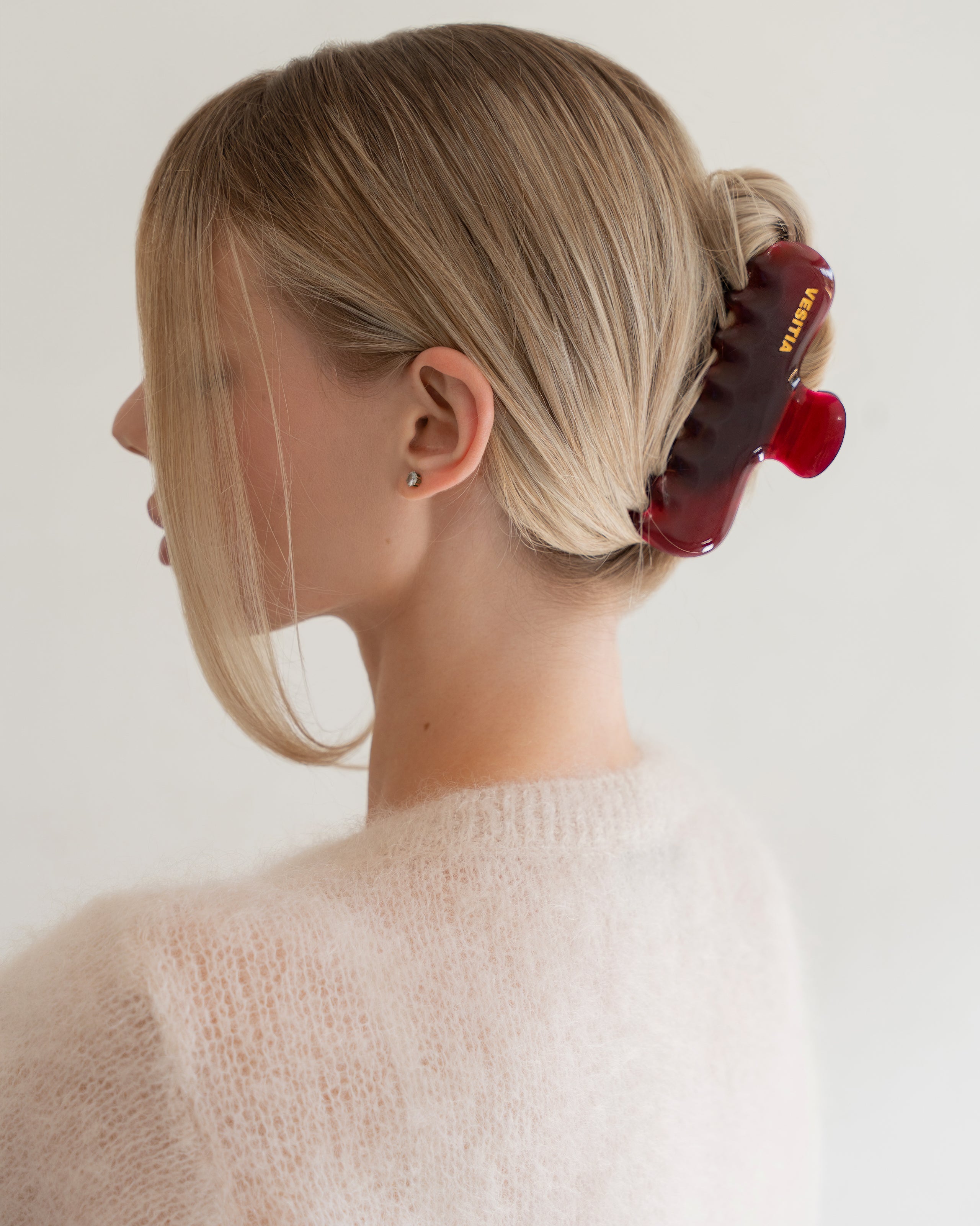 Woman with extra thick hair styling an updo using the VESITIA Maison Jumbo Claw Clip in Bordeaux.