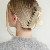 Woman with extra thick hair styling an updo using the VESITIA Maison Jumbo Claw Clip in Buttercream.