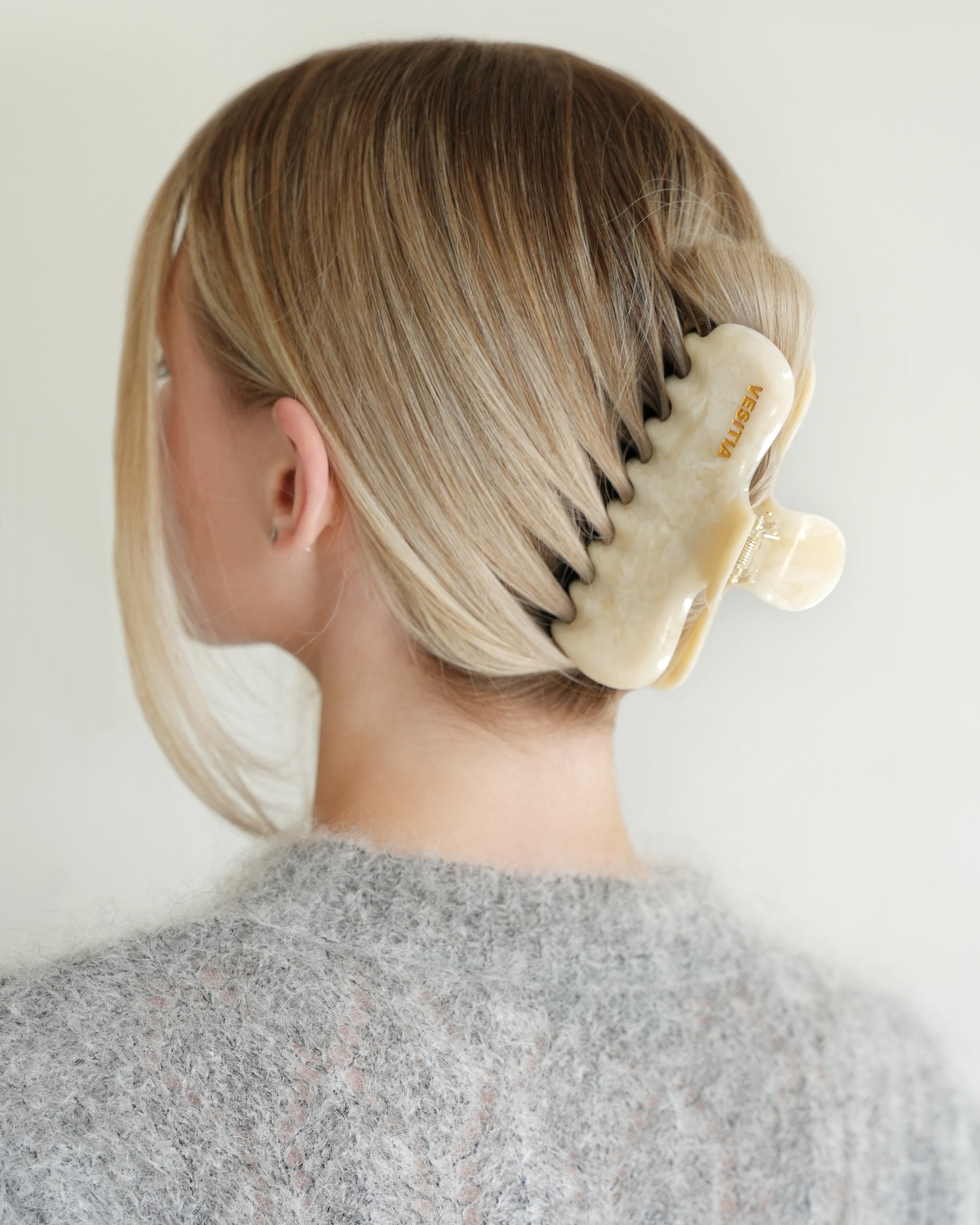 Woman with extra thick hair styling an updo using the VESITIA Maison Jumbo Claw Clip in Buttercream.