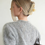 Woman with extra thick hair styling an updo using the VESITIA Maison Jumbo Claw Clip in Buttercream.