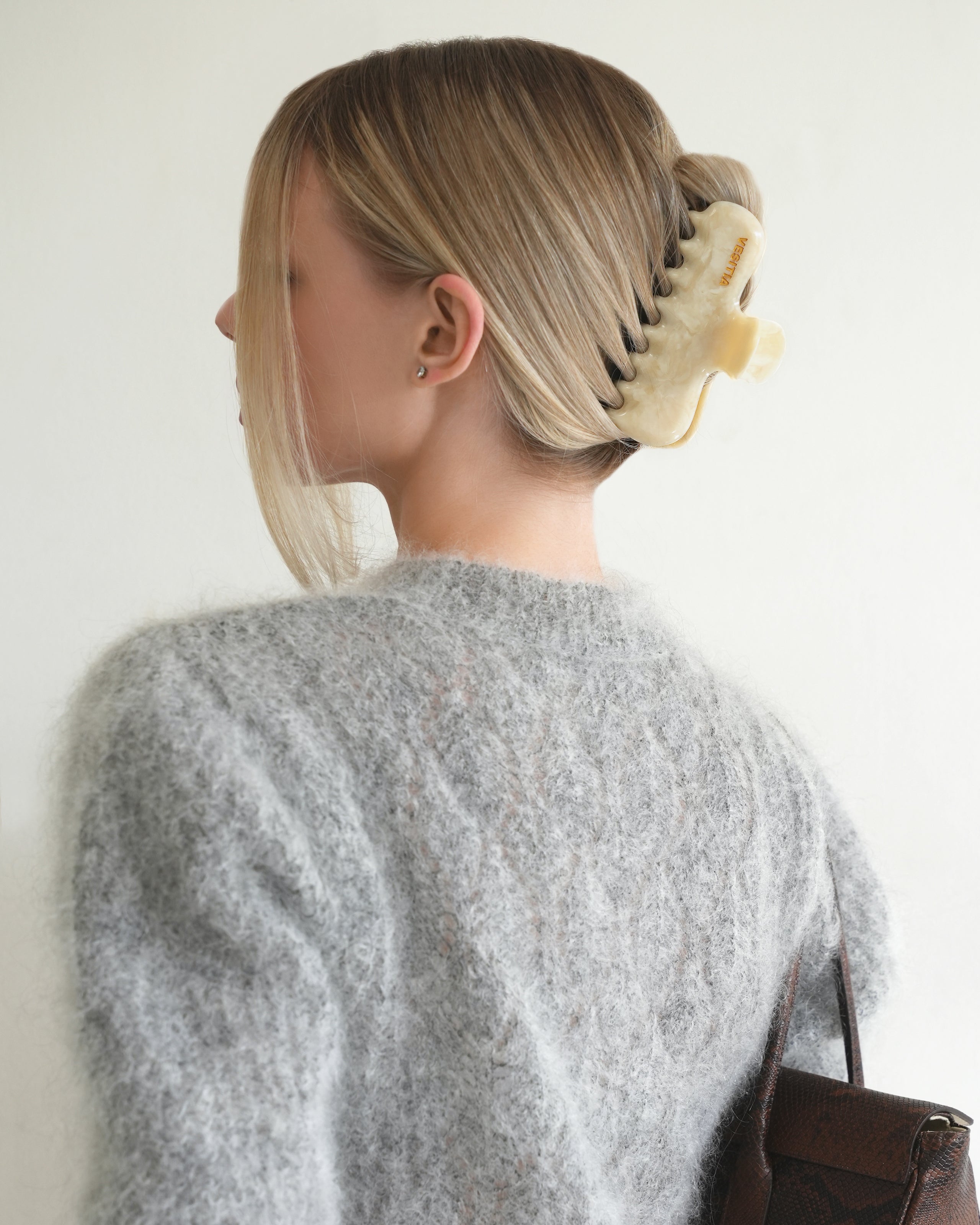 Woman with extra thick hair styling an updo using the VESITIA Maison Jumbo Claw Clip in Buttercream.