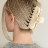 Woman with extra thick hair styling an updo using the VESITIA Maison Jumbo Claw Clip in Buttercream.