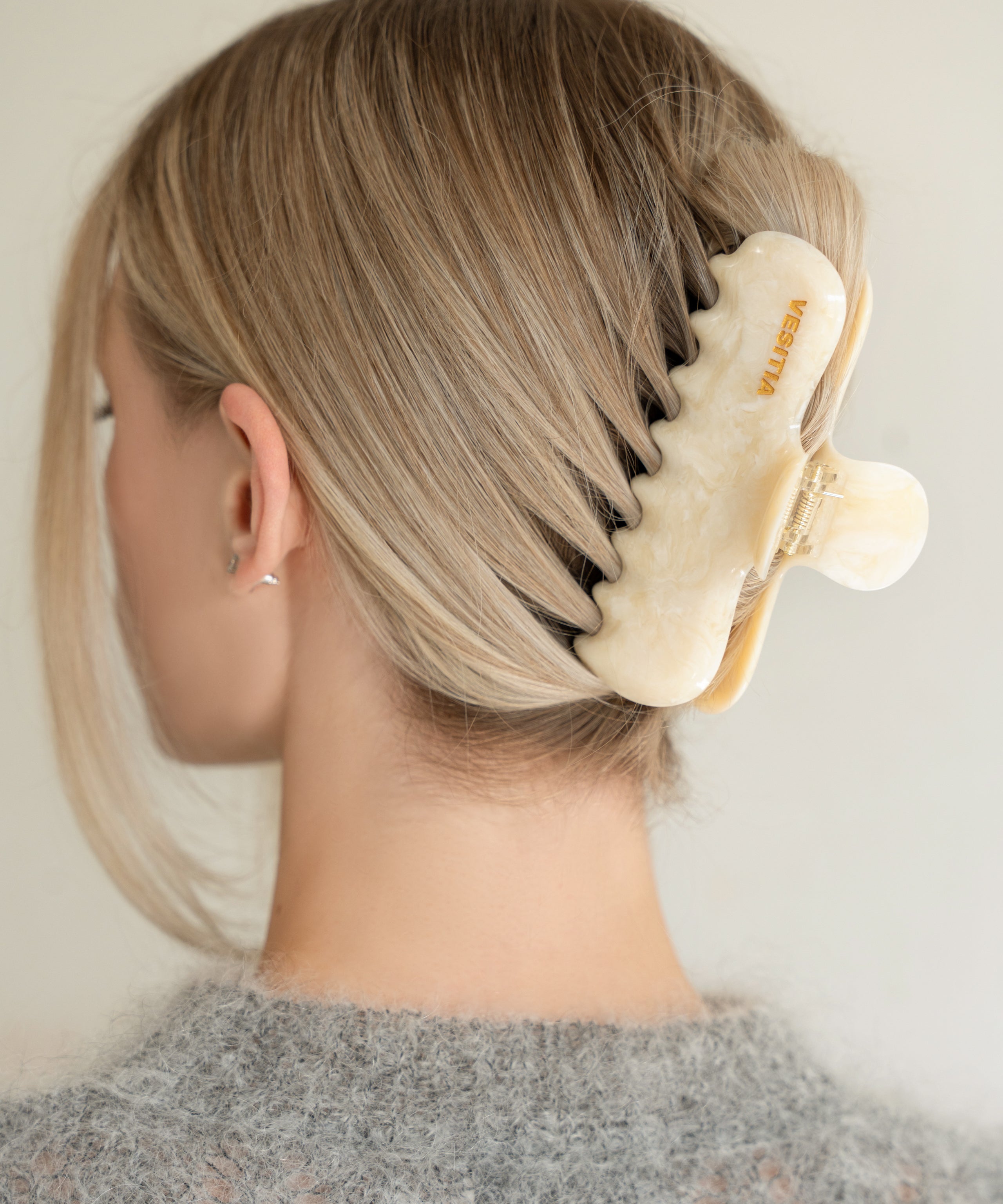 Woman with extra thick hair styling an updo using the VESITIA Maison Jumbo Claw Clip in Buttercream.