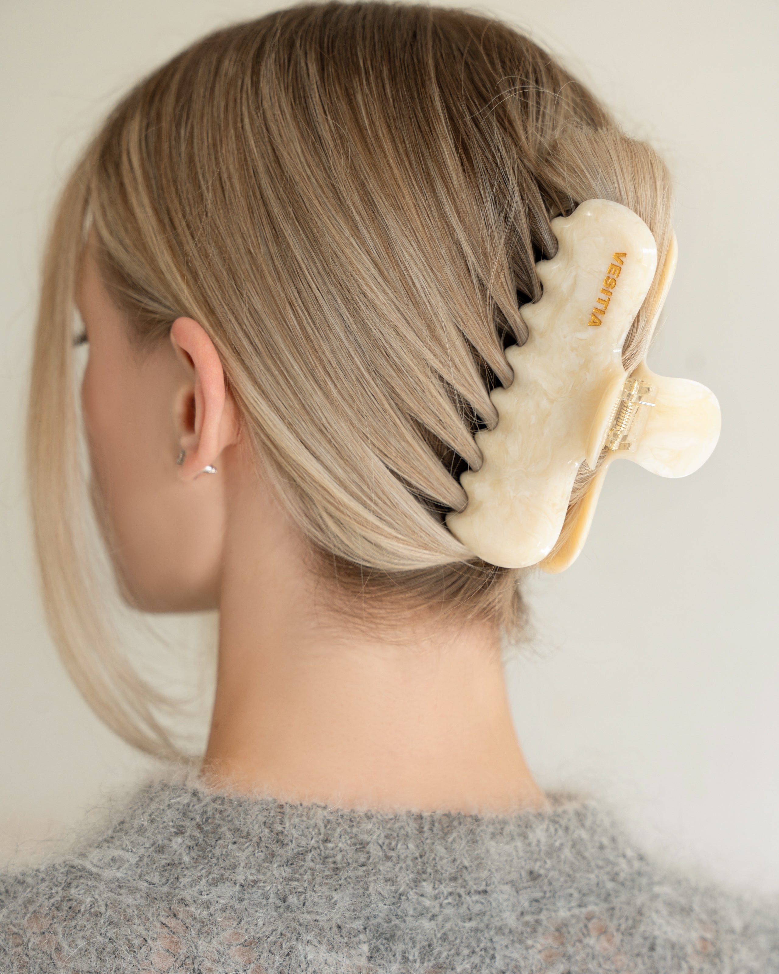 Woman with extra thick hair styling an updo using the VESITIA Maison Jumbo Claw Clip in Buttercream.