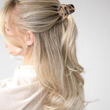 Blonde hair styled in a half up half down style with a VESITIA midi claw clip on a white background