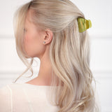 Woman with blonde hair wearing a green VESITIA claw clip against a white background