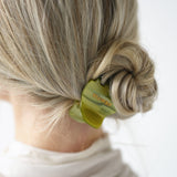 Person with a VESITIA green midi claw clip securing their bun on a white background