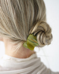 Person with a VESITIA green midi claw clip securing their bun on a white background