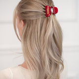 Blonde hair with a red VESITIA hair claw clip on a white background