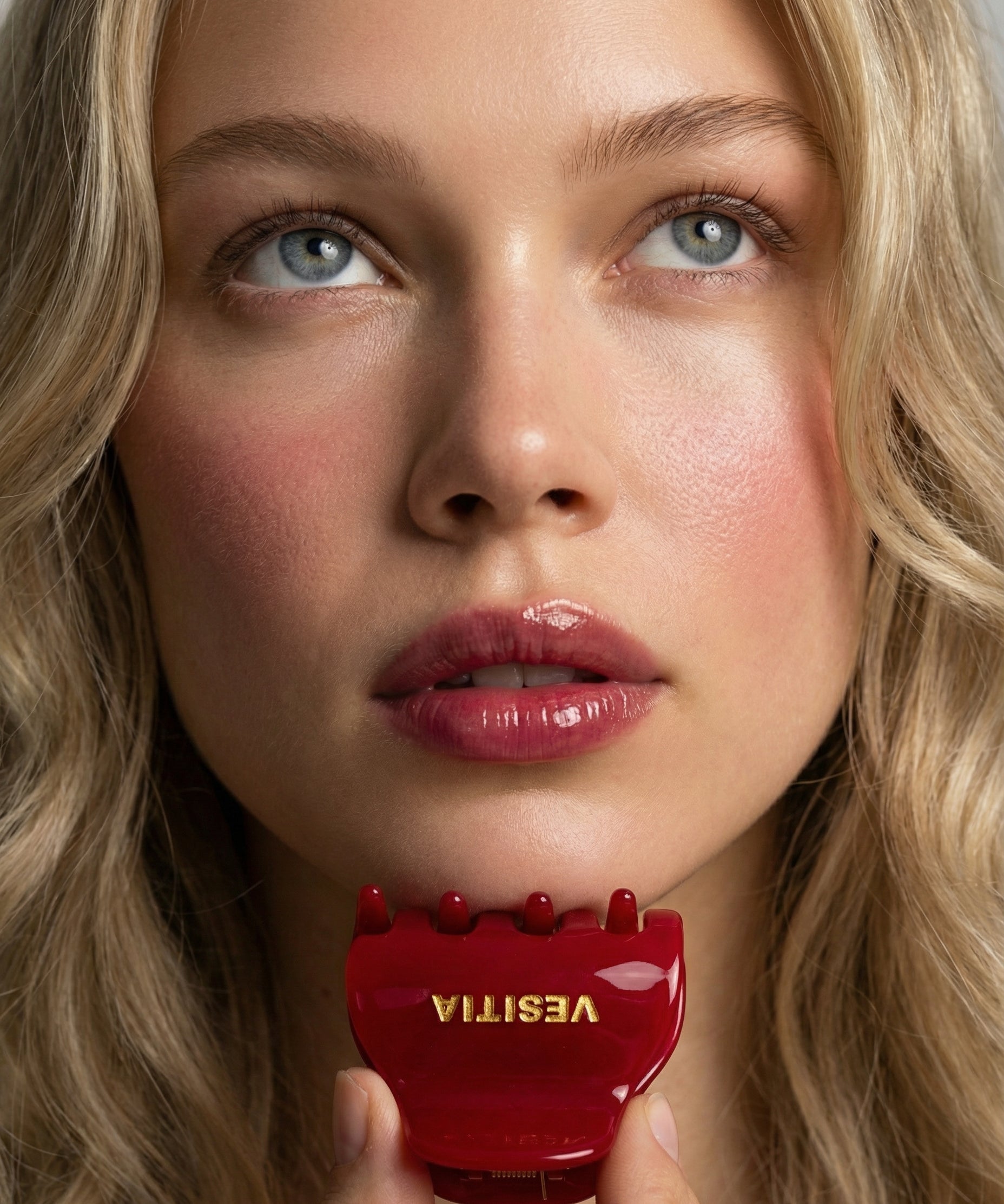 Woman holding a red VESITIA midi claw clip close to her face