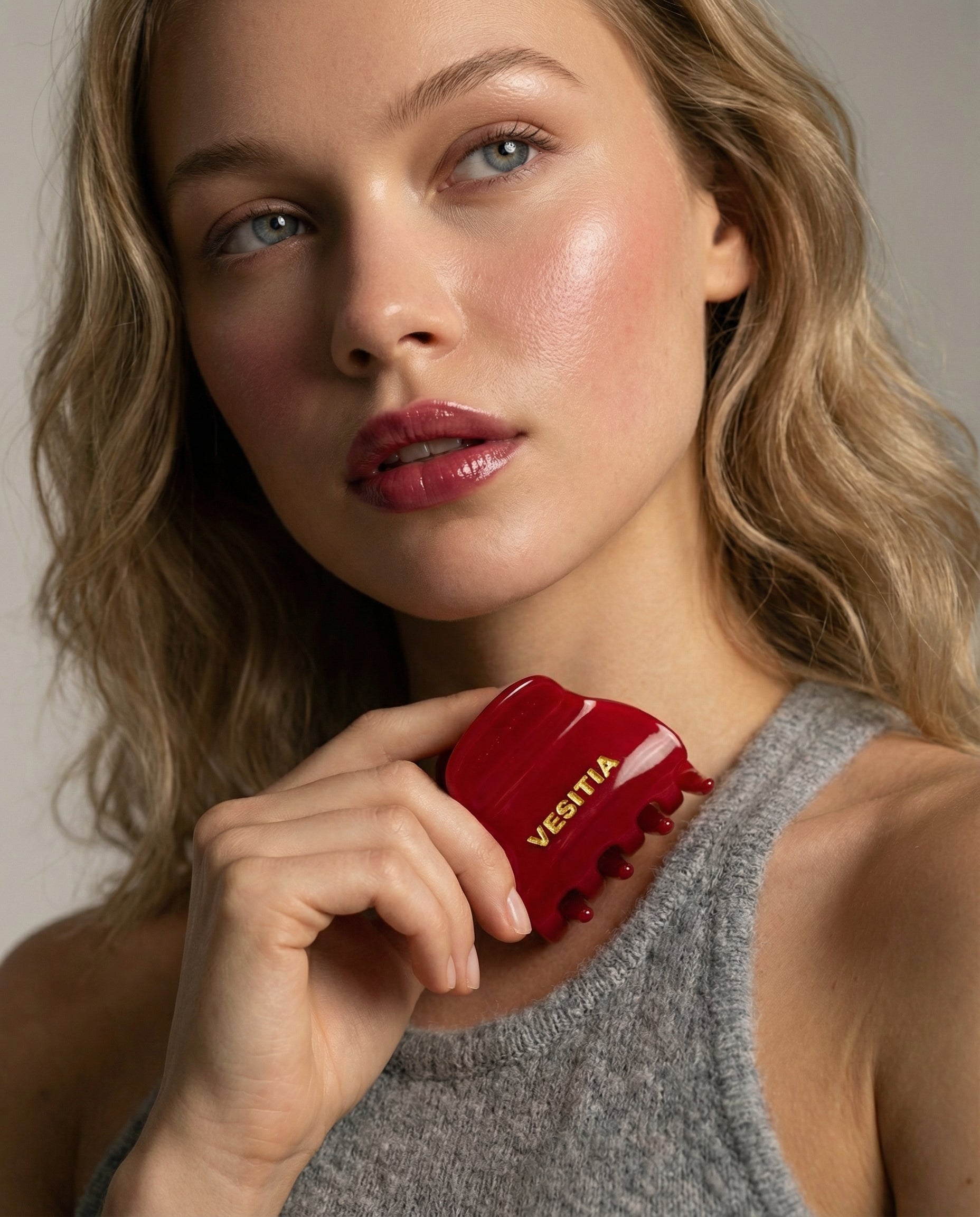Woman holding a red VESITIA midi claw clip against a neutral background