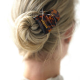 Close-up of a bun with a VESITIA midi claw clip on a blurred background
