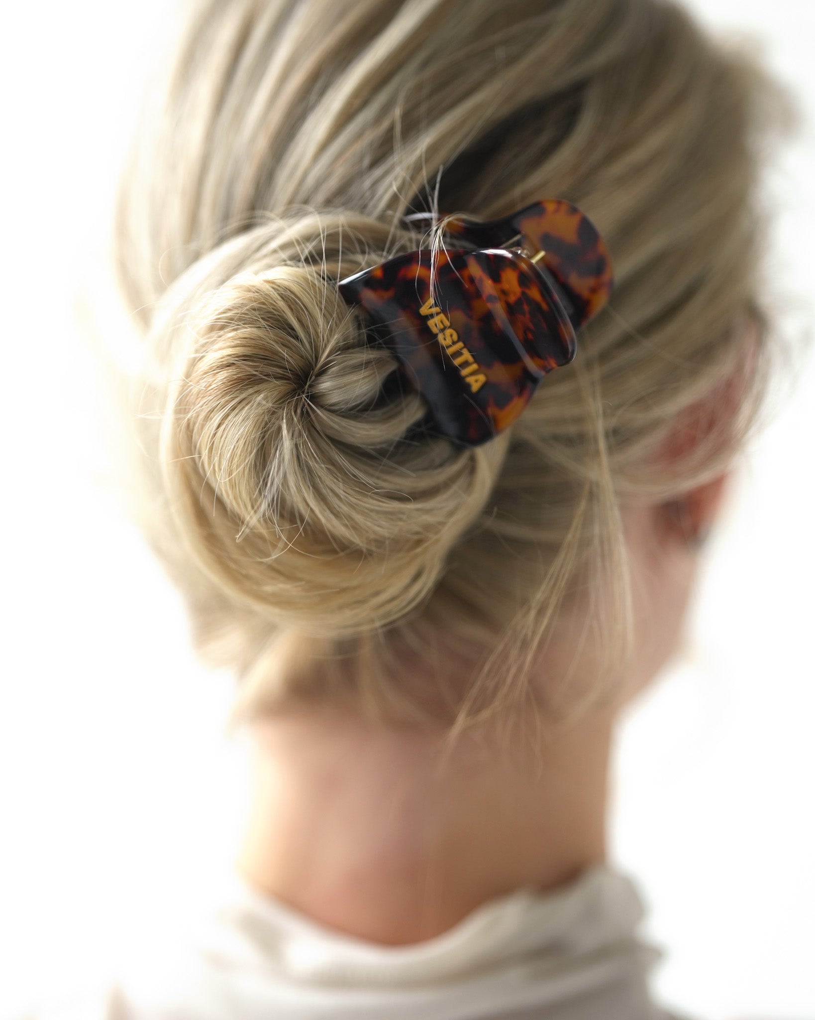 Close-up of a bun with a VESITIA midi claw clip on a blurred background