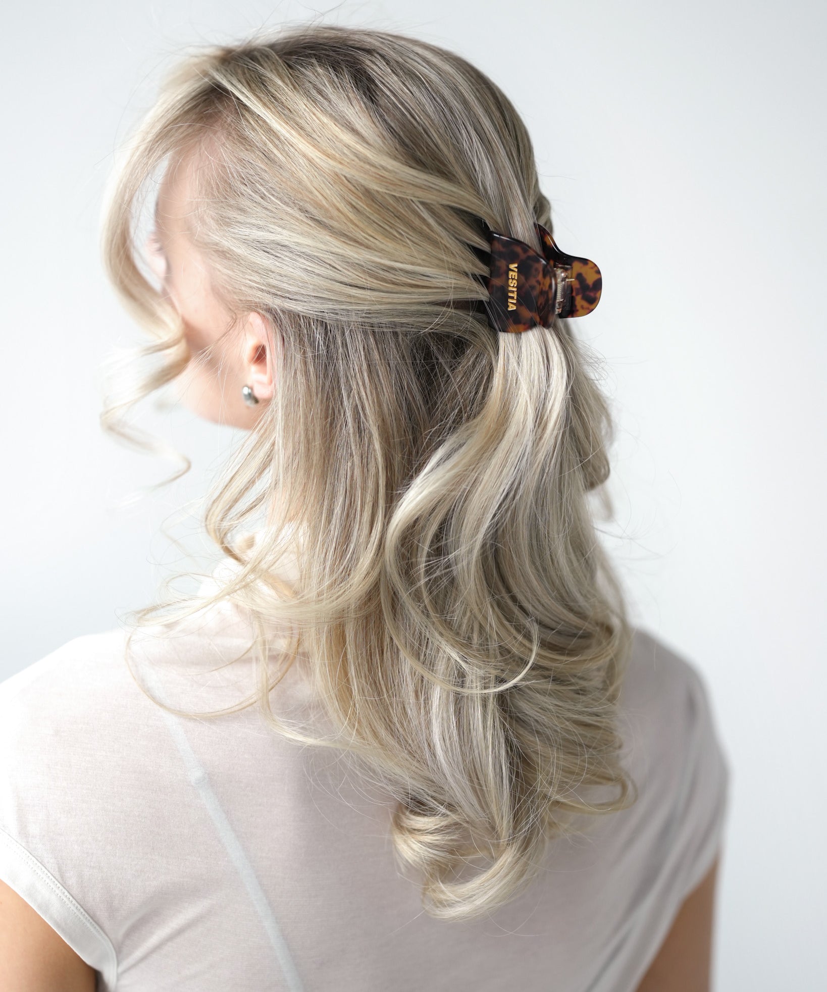 Person with blonde hair styled with a VESITIA midi claw clip on a white background