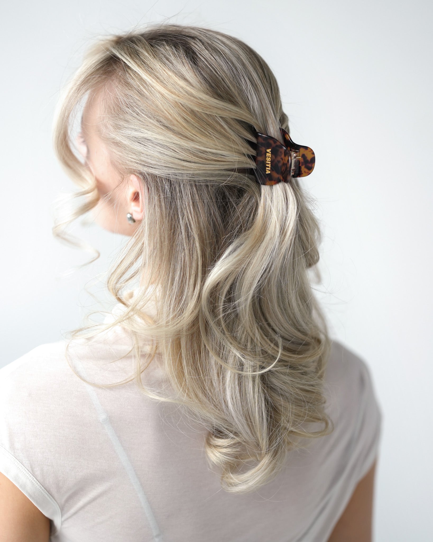 Person with blonde hair styled with a VESITIA midi claw clip on a white background