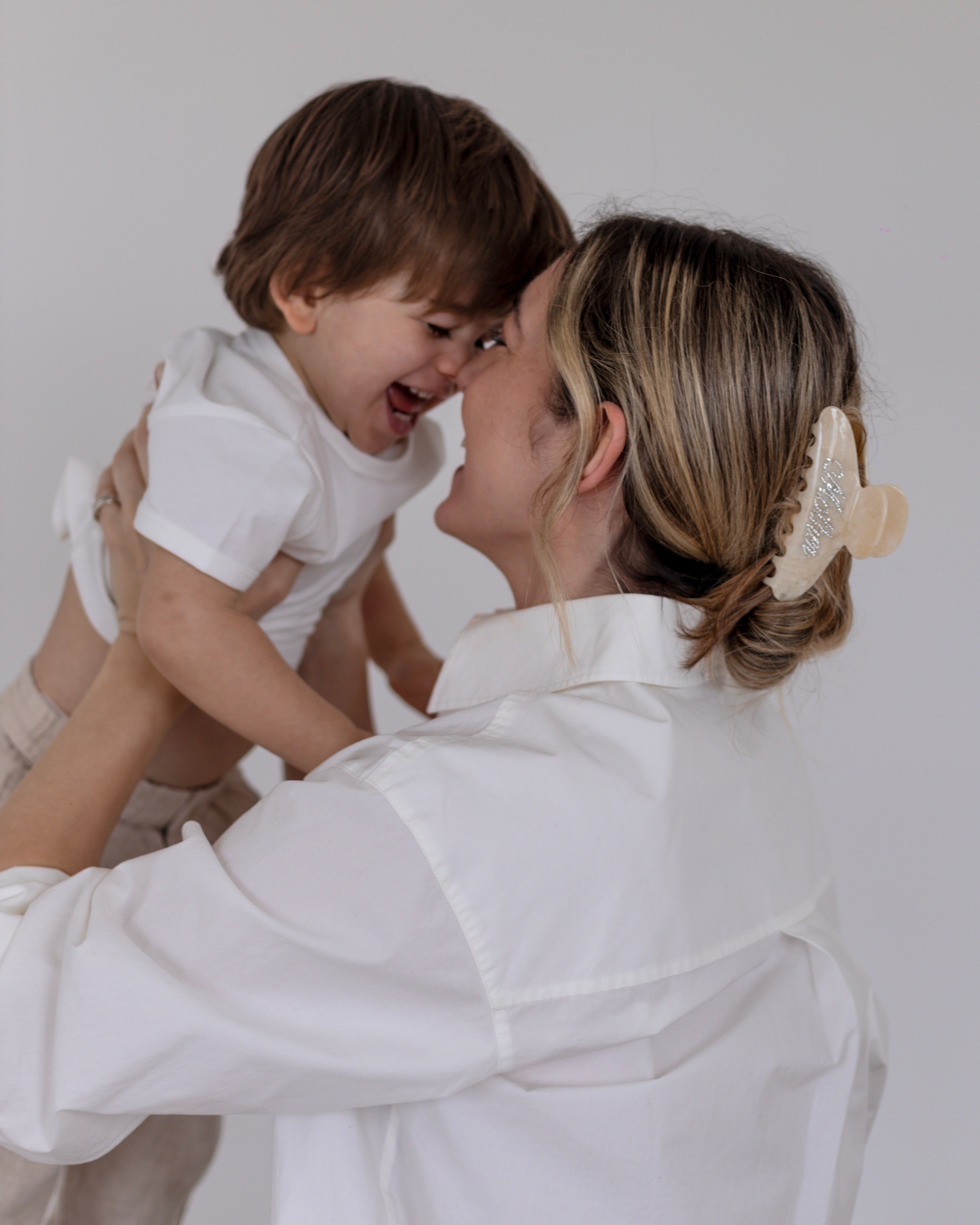 Woman wearing a VESITIA mother claw clip holding a child against a plain background