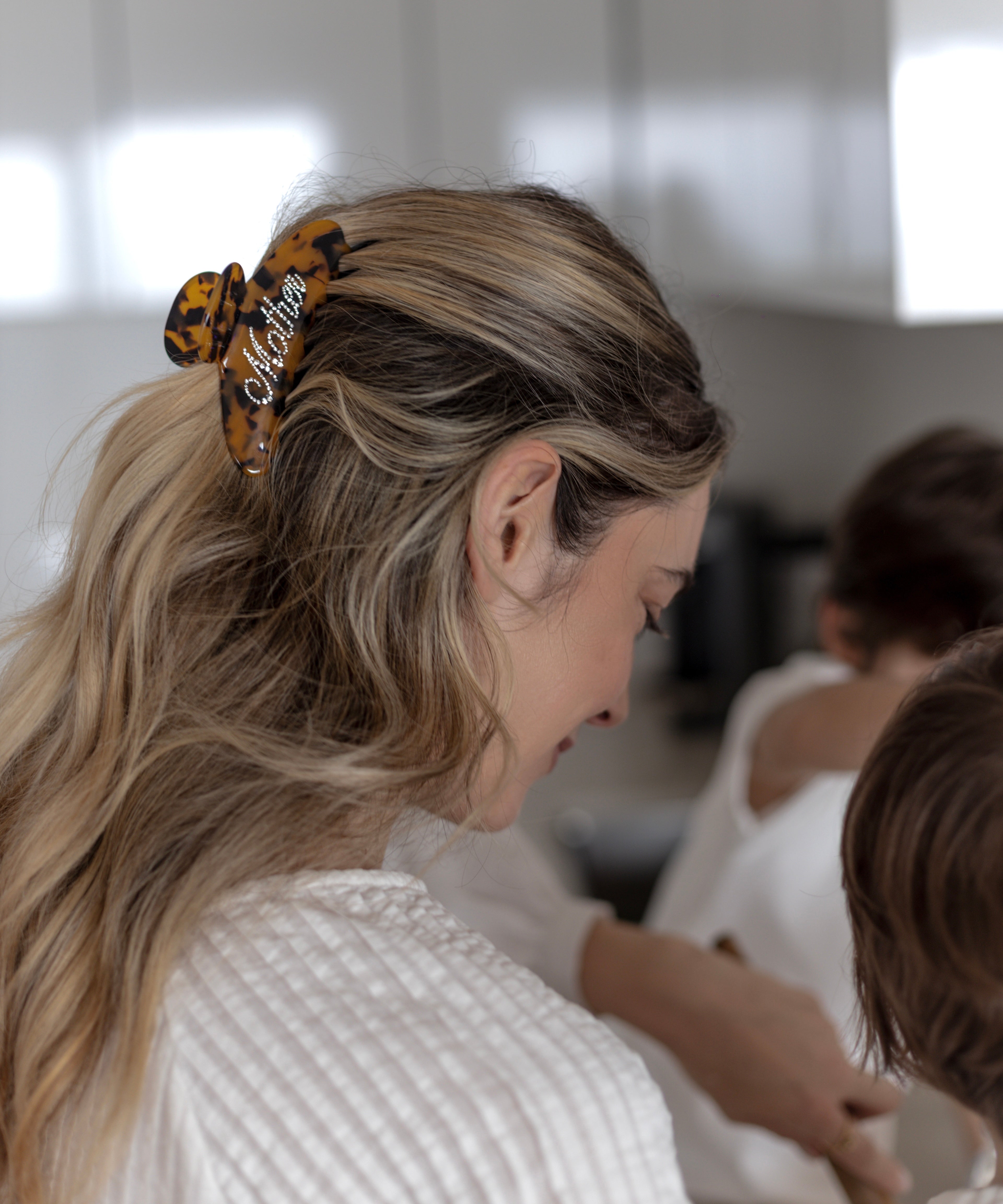 Woman with a VESITIA mother claw clip in her hair, looking down at a child.