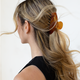 Person with  using a VESITIA hair claw clip on a plain background