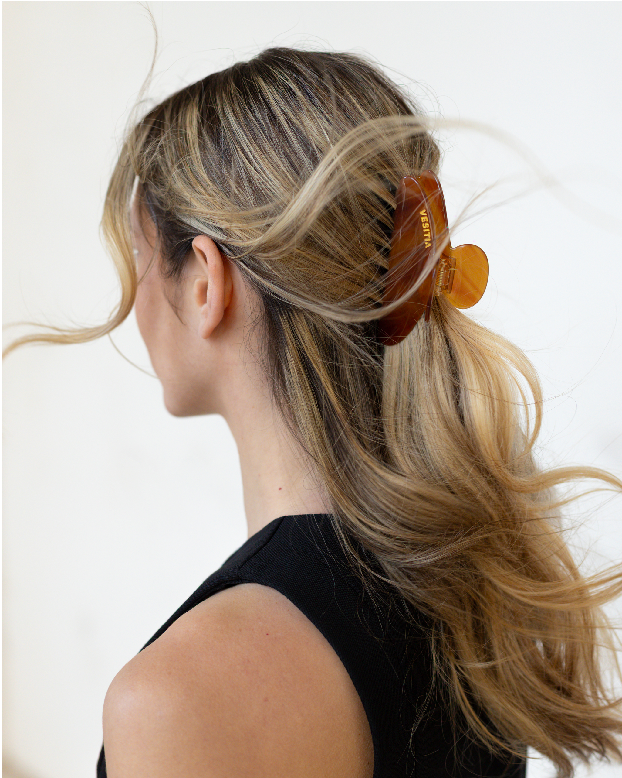 Person with  using a VESITIA hair claw clip on a plain background