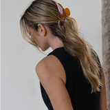 Person wearing an orange VESITIA hair claw clip and a black sleeveless top against a neutral background