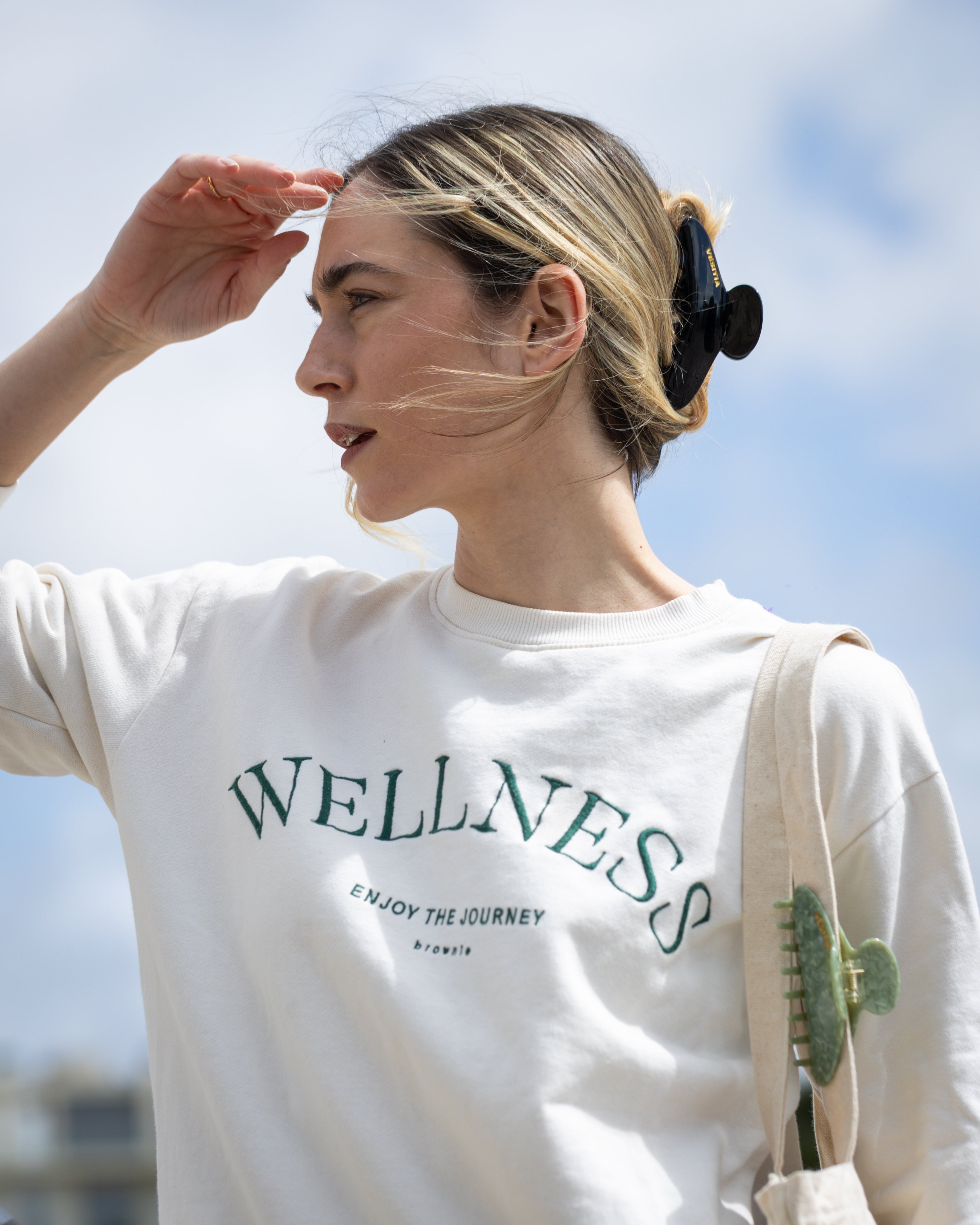 Woman wearing a white sweatshirt and a black VESITIA claw clip outdoors