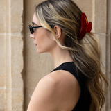 Woman with a red VESITIA hair claw clip in her hair against a stone wall background