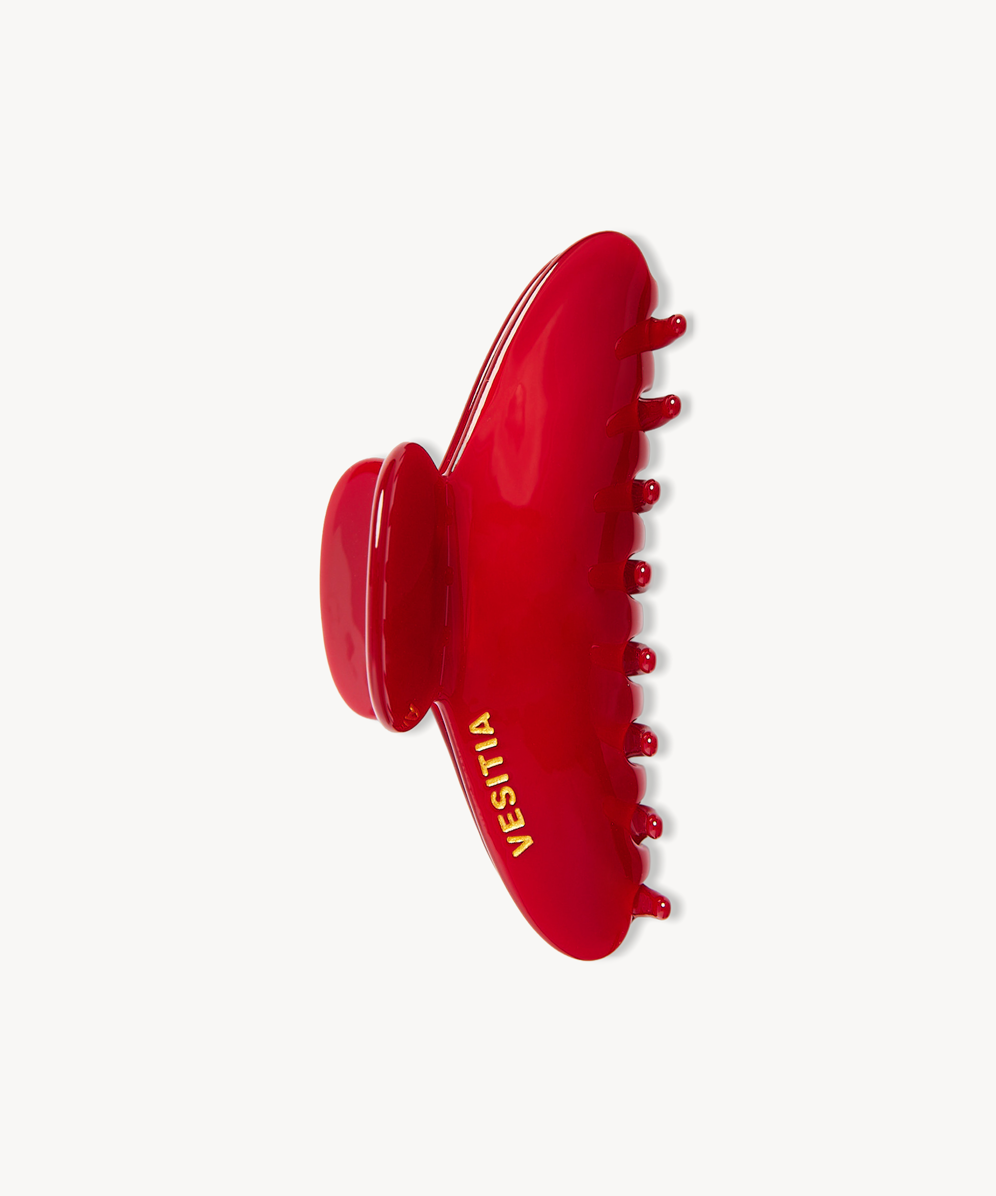 A glossy red hair claw clip with the brand name 'VESITIA' painted in gold, shown against a plain off-white background.