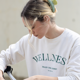 Person wearing a white sweatshirt and a green VESITIA claw clip in her hair, holding a bag.