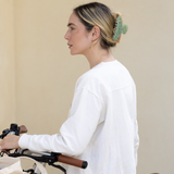 Woman in a white sweater with a bicycle, wearing a green VESITIA hair claw clip.